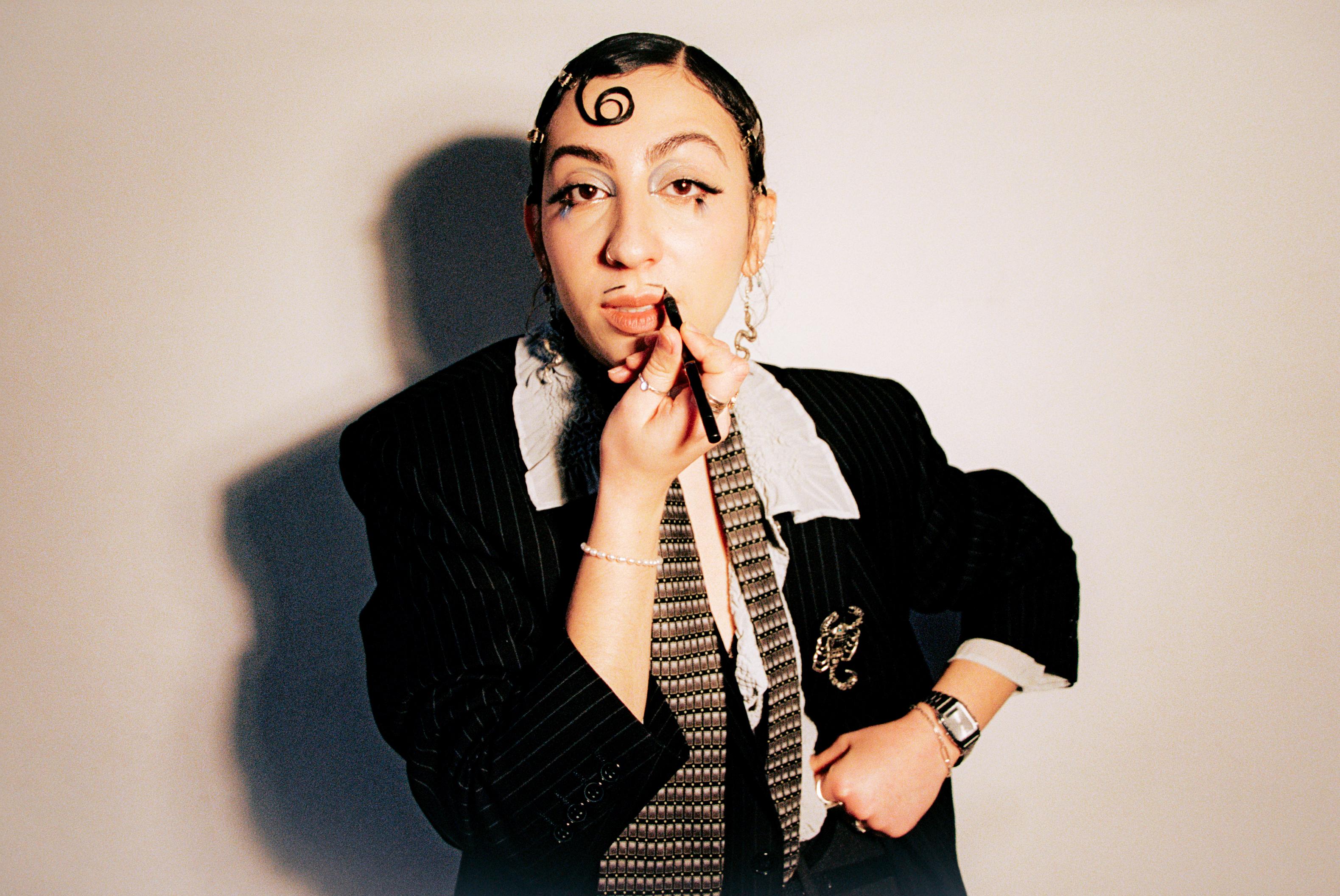 Rivkala applying lipstick in a wide editorial portrait