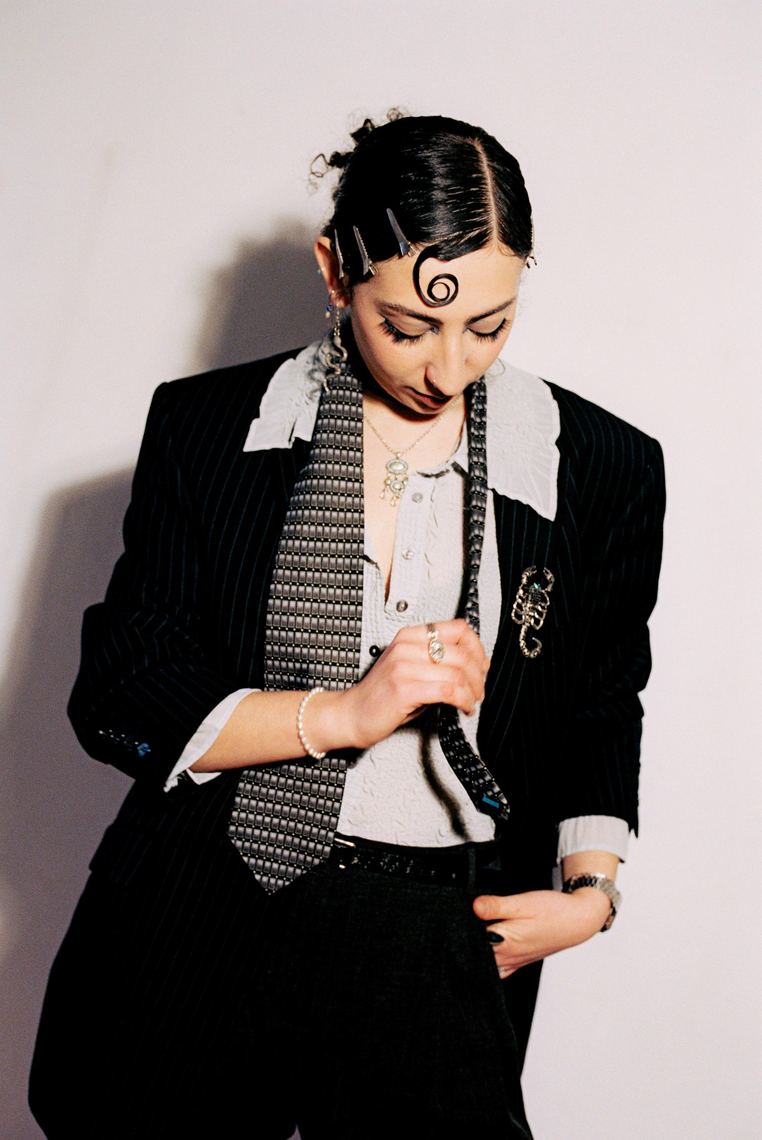 Rivkala looking down while adjusting a patterned tie
